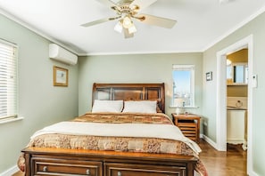 Une chambre à coucher avec un lit en bois, un ventilateur de plafond, une table de chevet et une fenêtre.