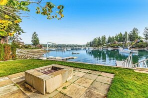 A marina with boats docked, a fire pit, and a grassy area. - 5BR luxury lake home with private beach & dock (Fox Island)