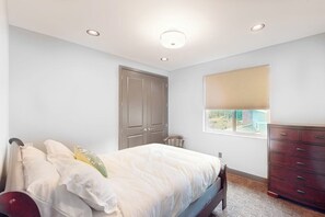 A bedroom with a bed, a dresser, a window with blinds, and a door. - 5BR luxury lake home with private beach & dock (Fox Island)