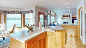 Una cocina moderna con una isla grande, armarios de madera y vistas al mar.