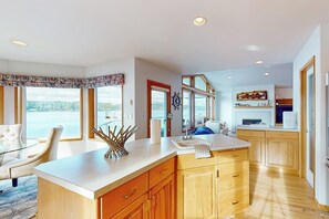 Une cuisine moderne dotée d’un grand îlot central, de meubles en bois et offrant une vue sur la mer.