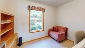 Una habitación con ventana, un sofá, una silla y una estantería.