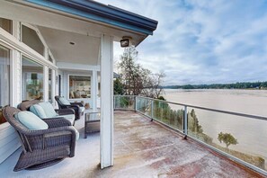 A covered outdoor area with wicker furniture and a view of a river. - 3 BR Waterfront home with beach access (Shelton)