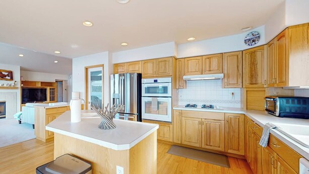 Una cocina moderna con armarios de madera, electrodomésticos de acero inoxidable y una isla central.