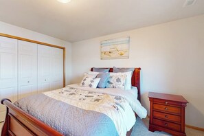 Une chambre à coucher comprenant un lit, une table de chevet, une commode et une œuvre d’art accrochée au mur.
