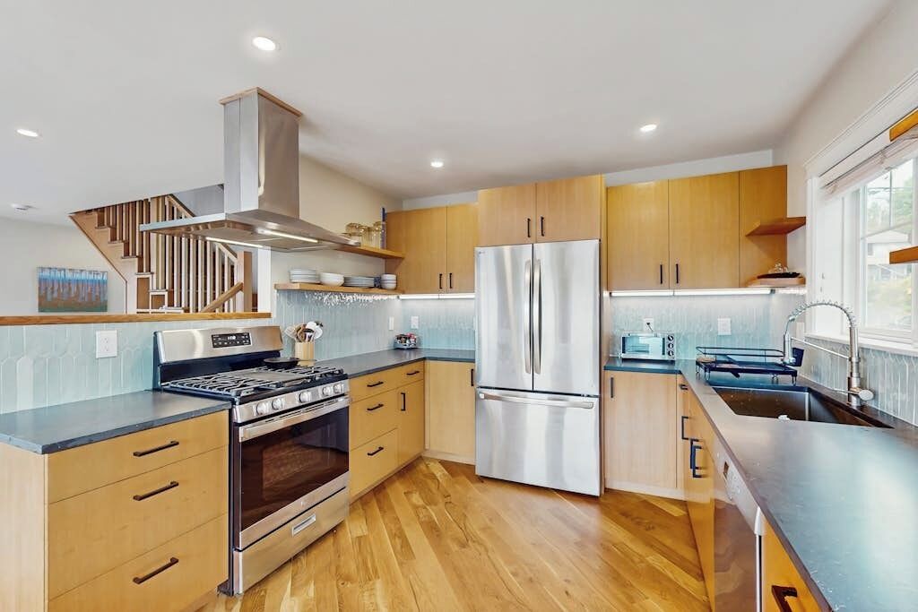 A modern kitchen with wooden cabinets, stainless steel appliances, and a built-in oven.