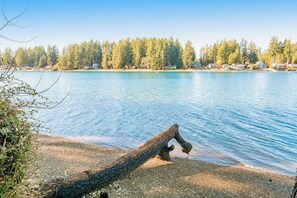A calm lake with a fallen tree trunk in the foreground and a forested shoreline in the background. - Amazing 3BR Bayview Dog Friendly - Balcony (Allyn)
