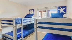 Quarto com beliches, relógio, arte com tema de estrelas-do-mar e janela com vista.