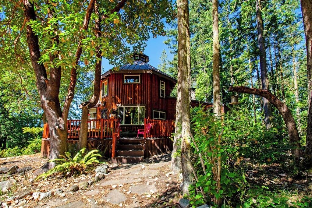 A rustic cabin with a wooden exterior, a porch, and a stone pathway leading to the entrance.