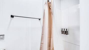 A bathroom with a white shower curtain, a towel rack, and a wall-mounted soap dispenser.