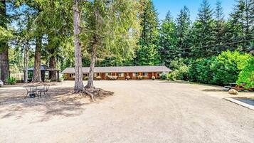 A lodge with a dirt driveway, a covered picnic area, and a row of cabins.