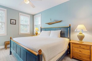 Ein Schlafzimmer mit einem Bett, Nachttischen, einem Deckenventilator und einem an der Wand befestigten Regal.