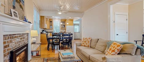 Uma sala de estar com lareira, um sofá, uma mesa de centro e um espaço de jantar com cadeiras e uma mesa.