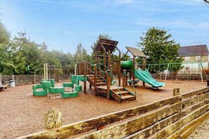 A playground with a slide, climbing structures, and swings. - 4BR Seabrook property - carriage house & yard (Pacific Beach)
