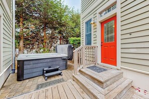 A wooden deck with a hot tub, a red door, and a staircase leading to a porch. - 4BR Seabrook property - carriage house & yard (Pacific Beach)
