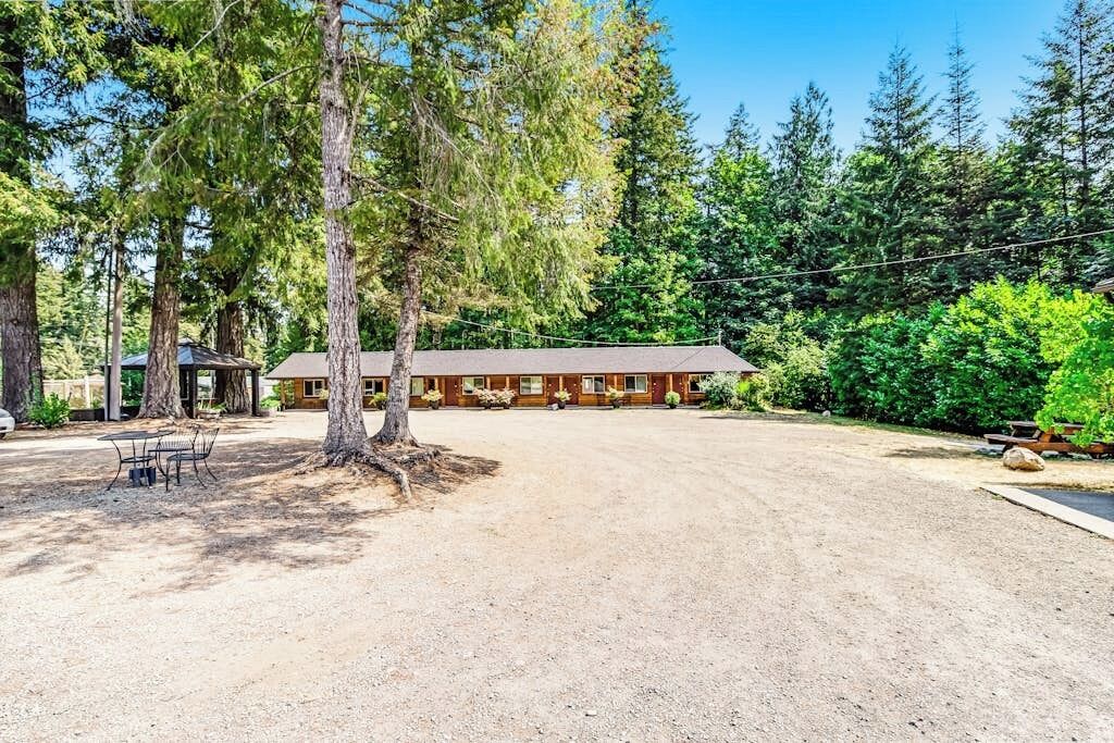 A lodge with a dirt driveway, a covered picnic area, and a row of cabins.