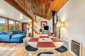 Un salon chaleureux avec un canapé bleu, une table ronde ornée de sets de table rouges et blancs, et un plafond en bois.