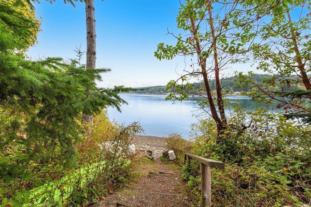 Un paisaje natural con un lago, un sendero de madera y abundante vegetación.