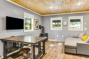 A modern living space with a wooden ceiling, a dining table with stools, a sofa, and a television mounted on the wall. - Dog-friendly, mountainview 1BR- walk to skiing (Snoqualmie Pass)