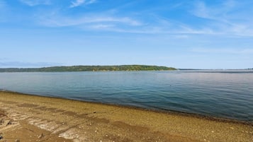Een rustig meer met een kiezelstrand en een afgelegen bosrijk eiland.