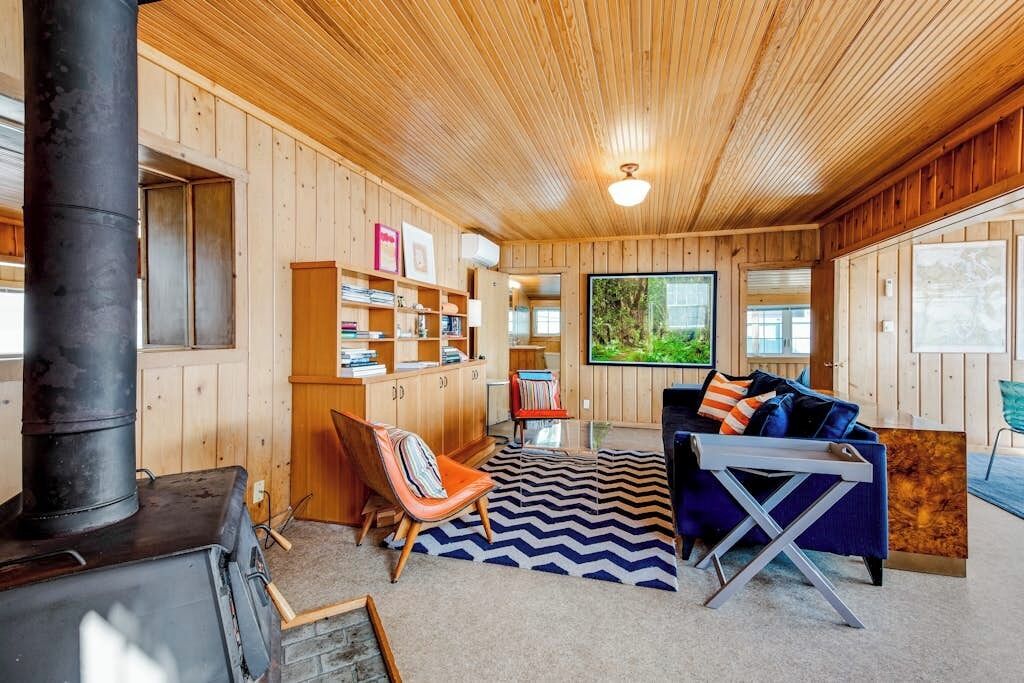 A cozy cabin interior with a wooden interior, a fireplace, a sofa, and a television.