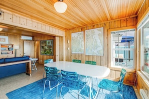 L’intérieur d’un chalet en bois comprend une table à manger, des chaises, un canapé et une grande fenêtre.