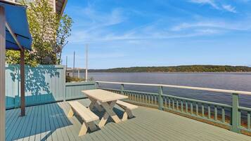 A wooden deck with a picnic table and benches overlooking a lake.