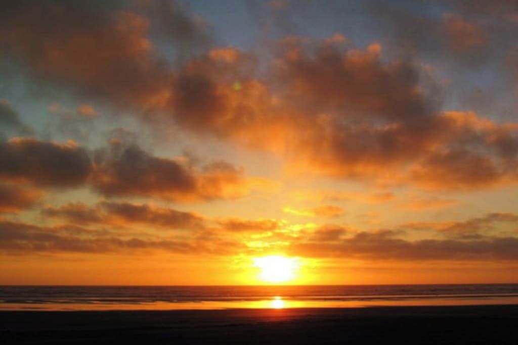 A sunset over the ocean with clouds in the sky.