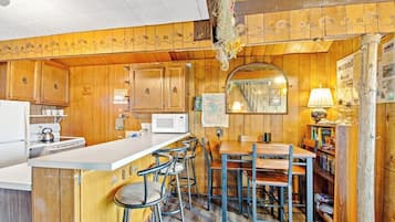 A kitchen with wooden cabinets, a microwave, a sink, and a bar area with stools.