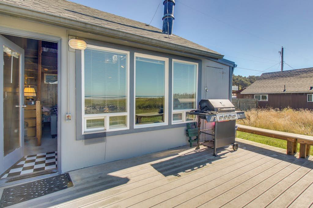 A house with a deck, a grill, and a door leading to a room.