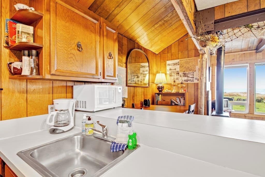 A kitchen with wooden cabinets, a white countertop, a sink, a coffee maker, and a window with a view.