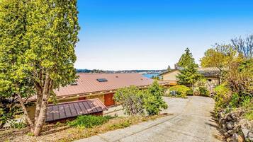A residential property with a paved driveway, a red-roofed building, and a view of the ocean.