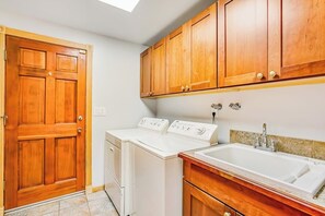Un lavadero con dos lavadoras, una puerta de madera y un lavabo con encimera.