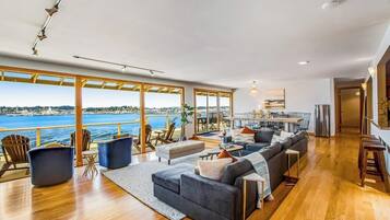 A spacious living area with a large sofa, a dining table, and a view of the sea.