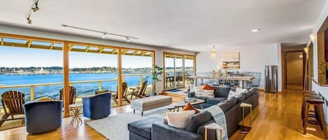 A spacious living area with a large sofa, a dining table, and a view of the sea.