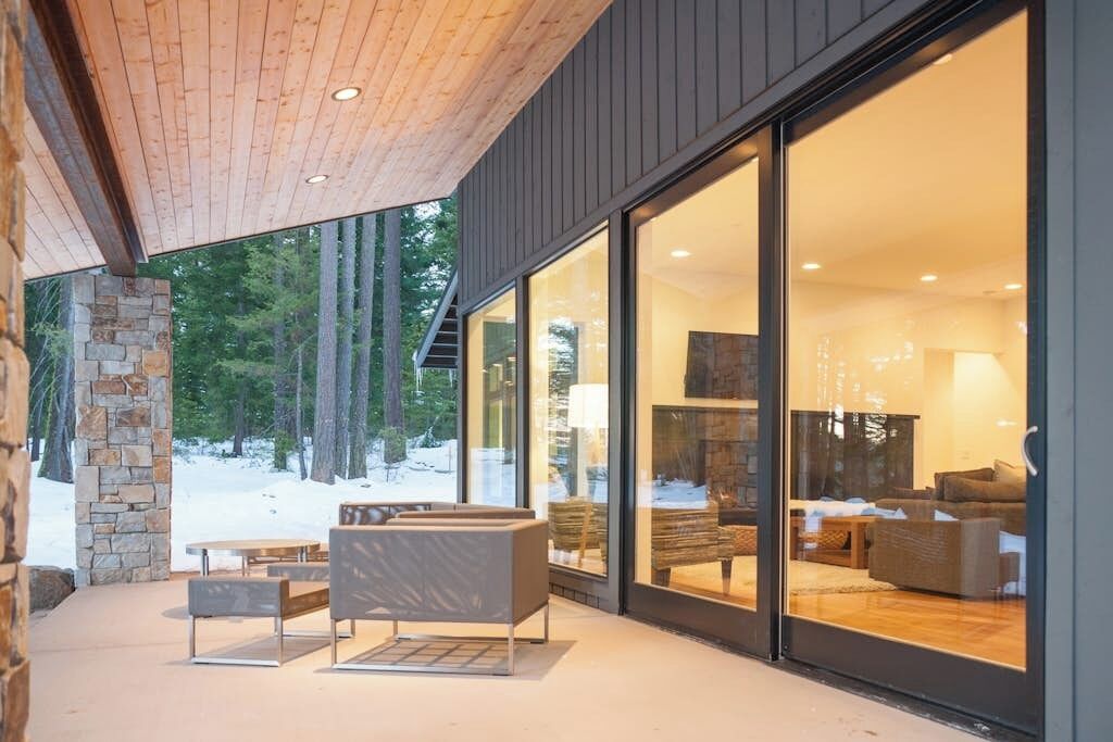 A modern interior with a stone column, large glass doors, and a seating area with a fireplace.