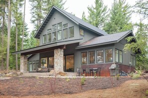 A modern two-story house with a stone foundation, large windows, and a covered patio area. - 4BR tree-lined manor with hot tub, firepit, grill (Cle Elum)