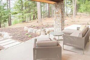An outdoor seating area with a stone pillar, a round table, and a sofa. - 4BR tree-lined manor with hot tub, firepit, grill (Cle Elum)