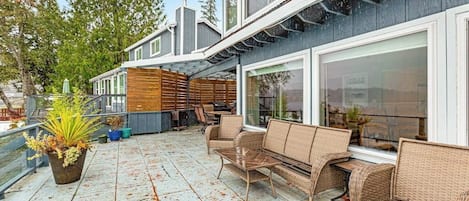 A covered outdoor patio with wicker furniture and potted plants.