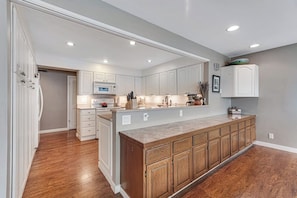 A spacious kitchen with wooden cabinets, a marble countertop, and recessed ceiling lights. - 2BR lakefront home - kayaks, grill, beach access (Olympia)