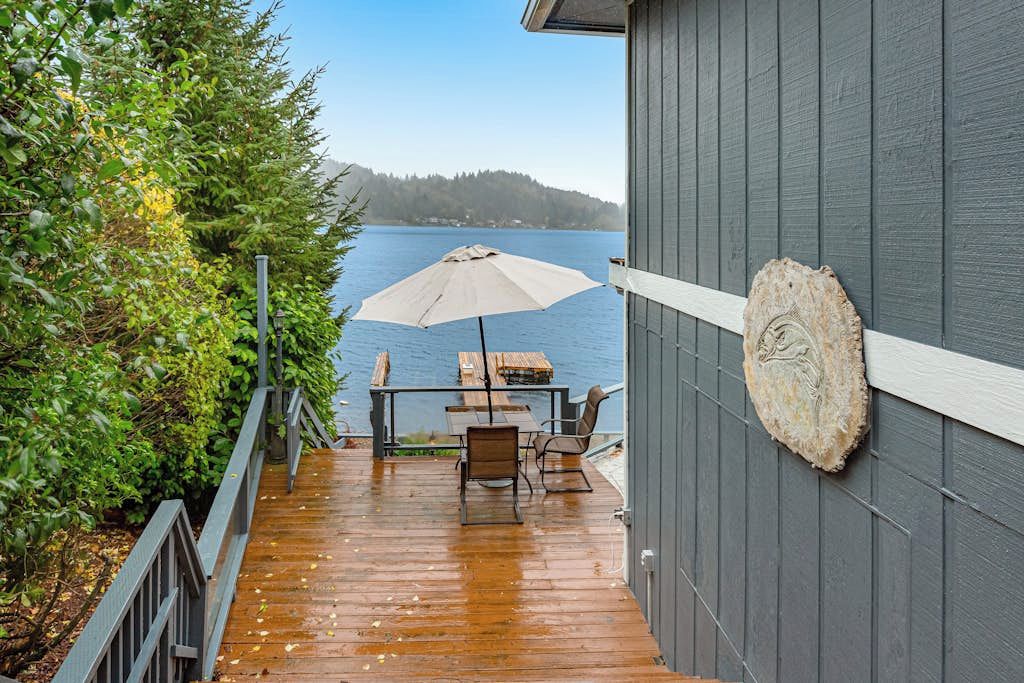 A wooden deck with a table and chairs, overlooking a body of water.