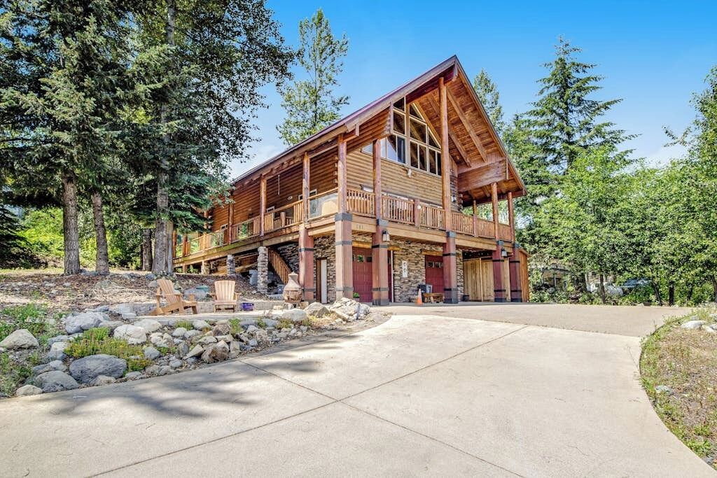 A large wooden cabin with a balcony, surrounded by trees.