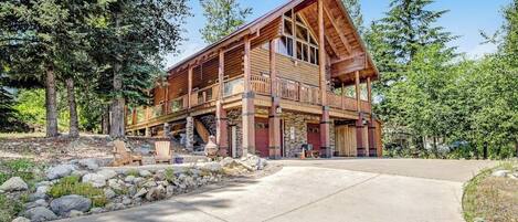 A large wooden cabin with a balcony, surrounded by trees.