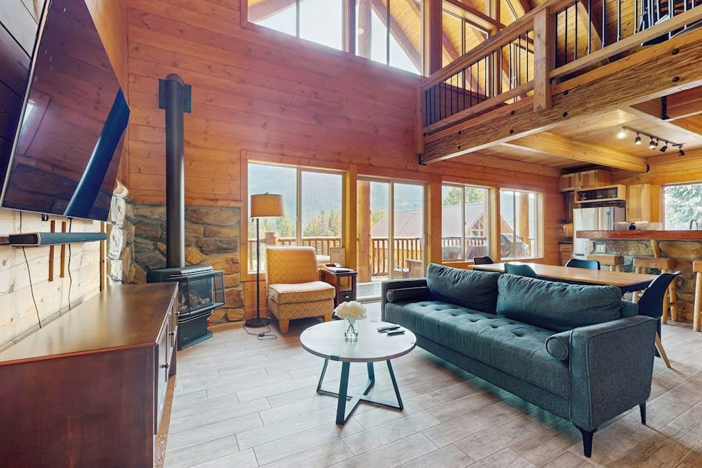 A spacious living area with a fireplace, a sofa, a dining table, and a kitchen in the background.