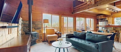 A spacious living area with a fireplace, a sofa, a dining table, and a kitchen in the background.