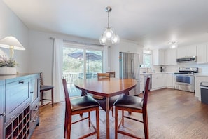 Een moderne keuken met witte kasten, roestvrijstalen apparatuur en een houten eettafel met vier stoelen.