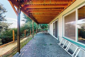 Un espace extérieur abrité, doté d’un sol en gravier, de poutres en bois et d’une table avec des chaises.