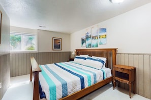 Une chambre à coucher avec un lit en bois, une table de chevet, une chaise et une fenêtre.