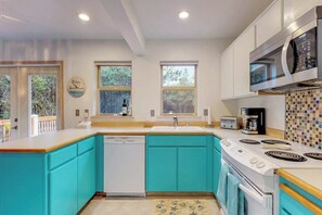A kitchen with a dishwasher, stove, microwave, and a window with a view of trees. - 3BR Dog Friendly - Hot Tub - Fireplace (Westport)