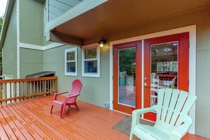 A wooden deck with two Adirondack chairs, a red door, and a covered area with a grill. - 3BR Dog Friendly - Hot Tub - Fireplace (Westport)